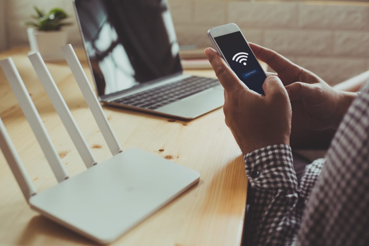 Closeup,Of,A,Wifi,Router,And,A,Man,Using,Smartphone
